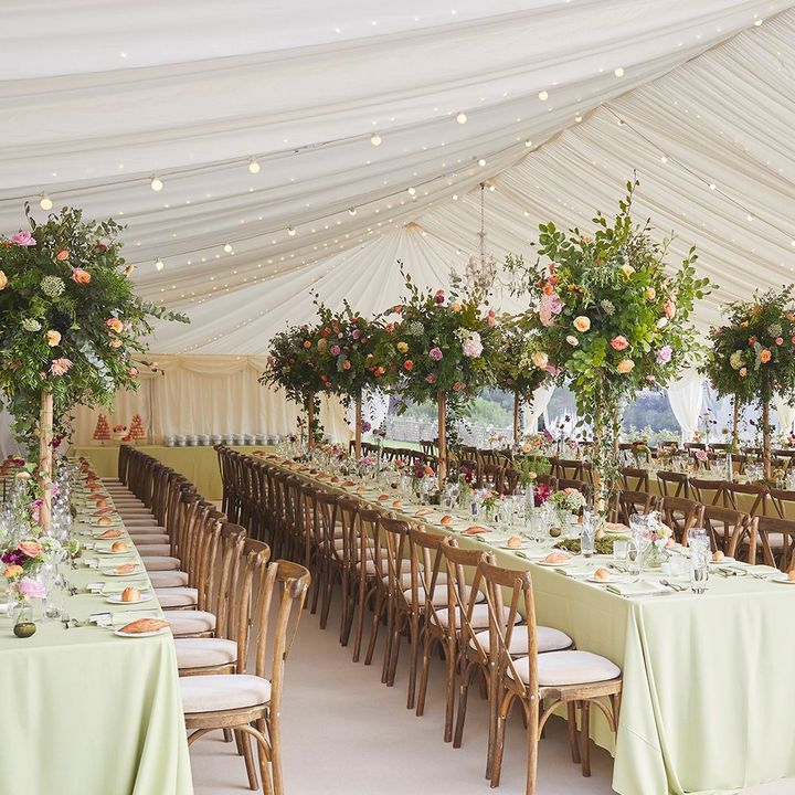 A tent with tables and chairs set up for a wedding reception