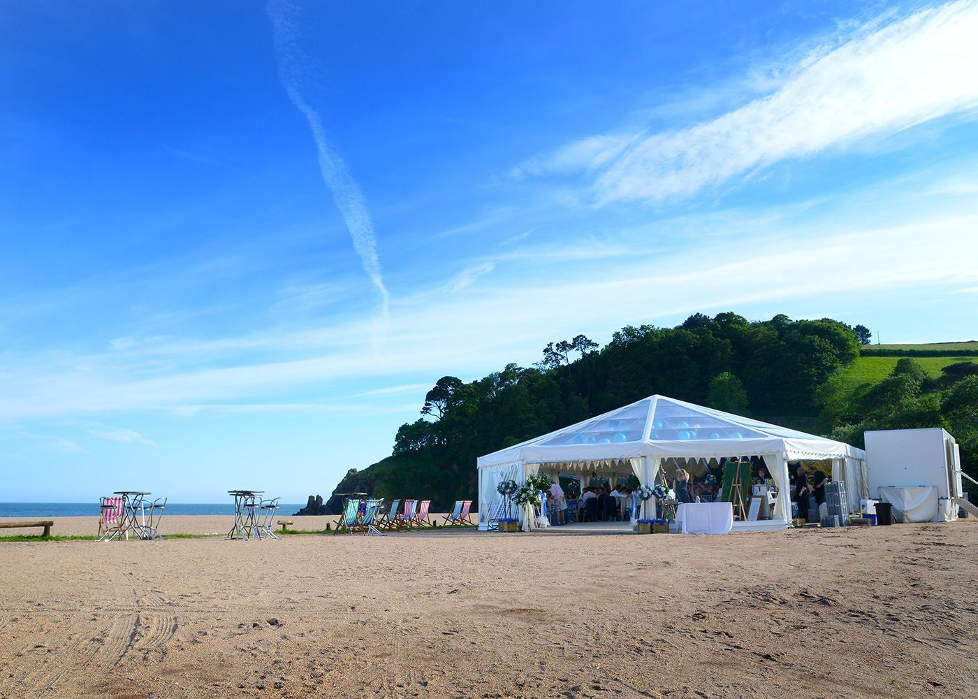 A large white tent is sitting on top of a sandy beach.