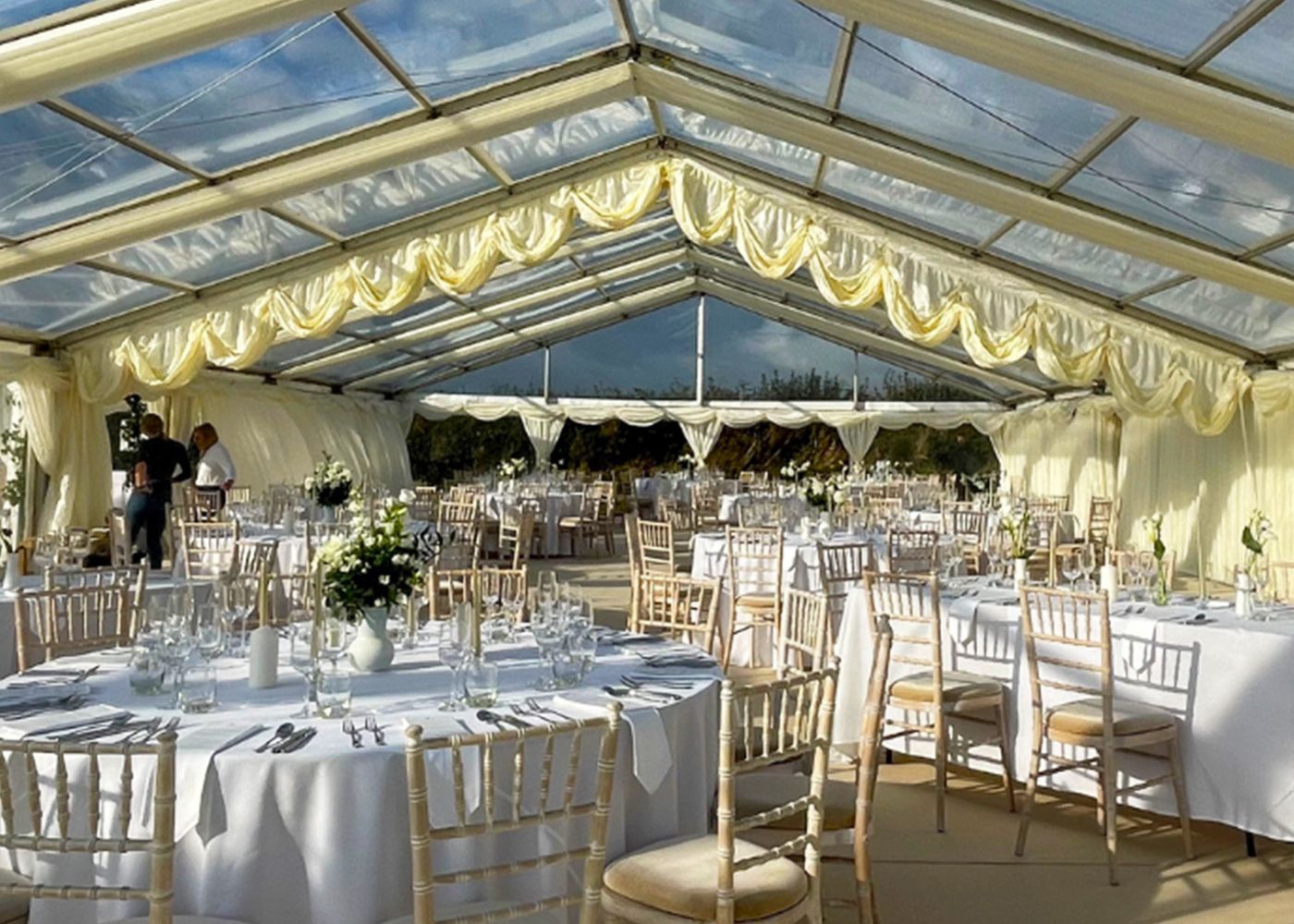 A large tent with tables and chairs set up for a wedding reception.
