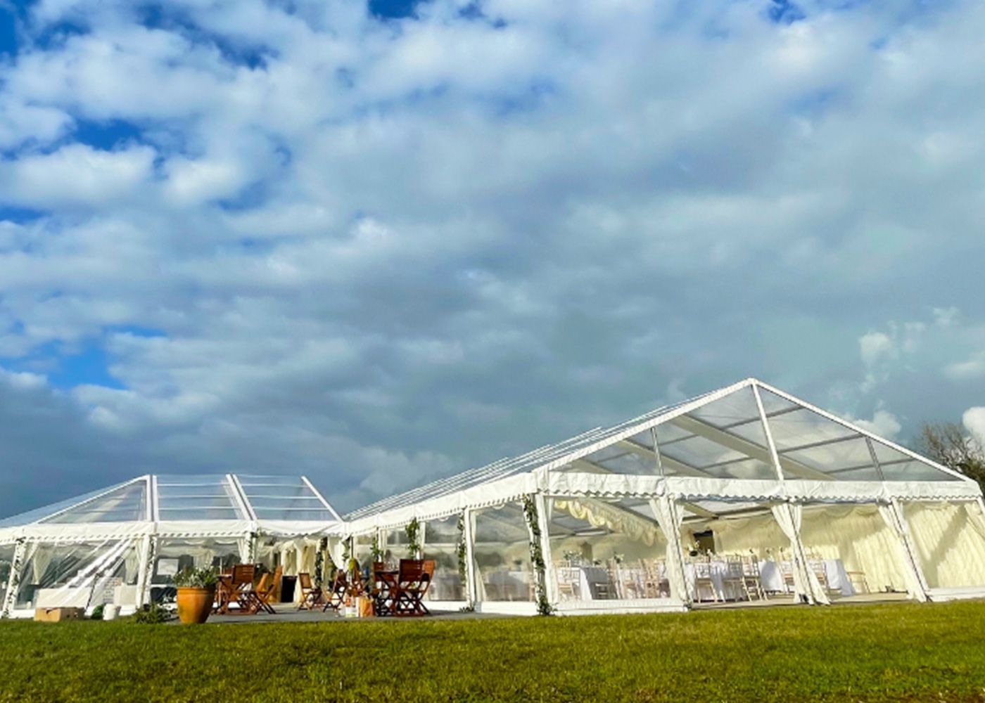 A large clear tent is sitting in the middle of a grassy field.