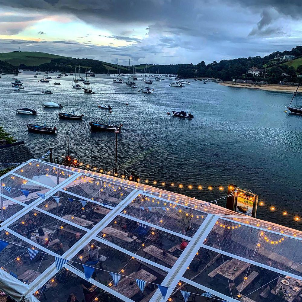 A clear tent overlooking a body of water with boats in it.