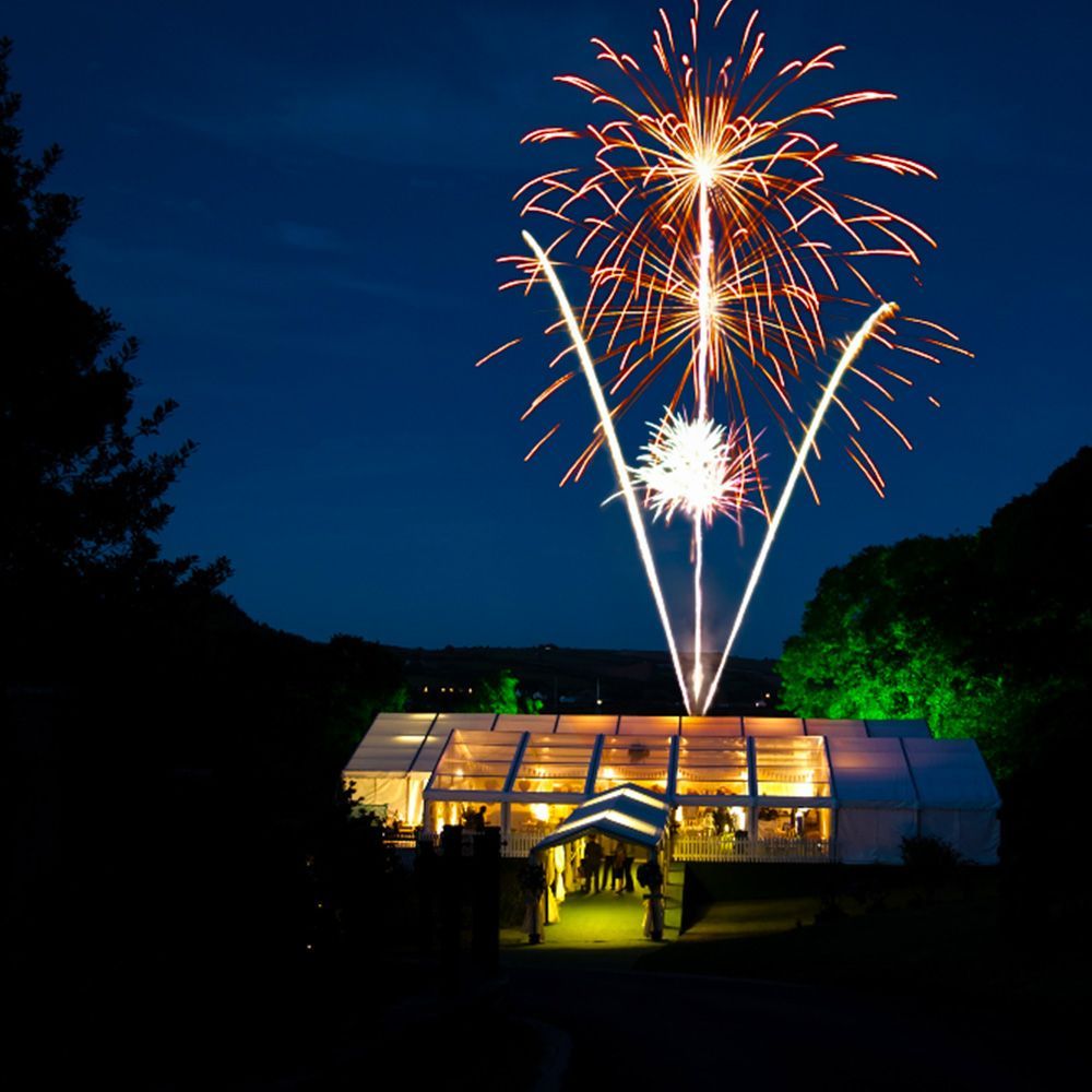 Fireworks are displayed over a clear tent at night