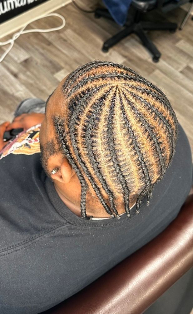 Close-up of braided hair styled in neat curved rows on a person resting in a chair.