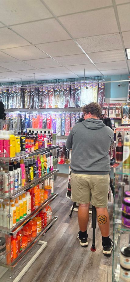 Person browsing shelves in a convenience store aisle, seen from behind.