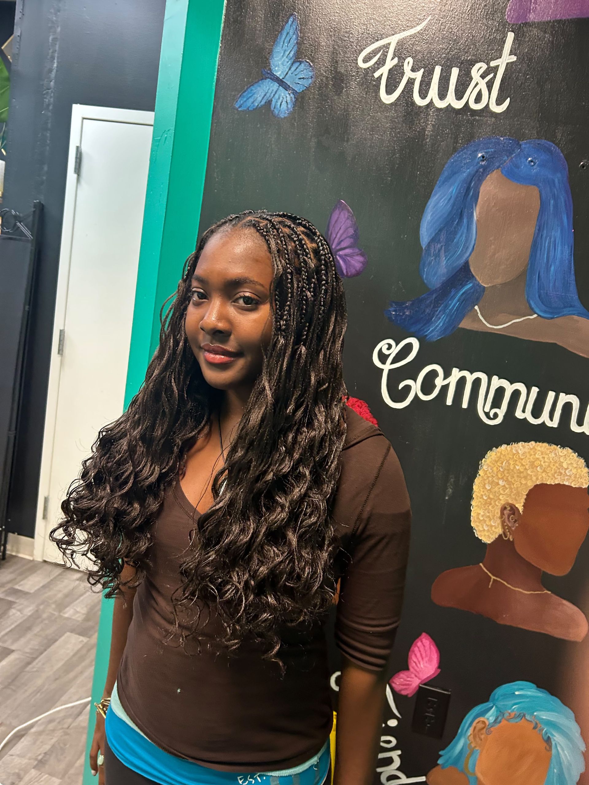 Woman standing in front of a mural with “Trust” and “Community” text and butterfly art