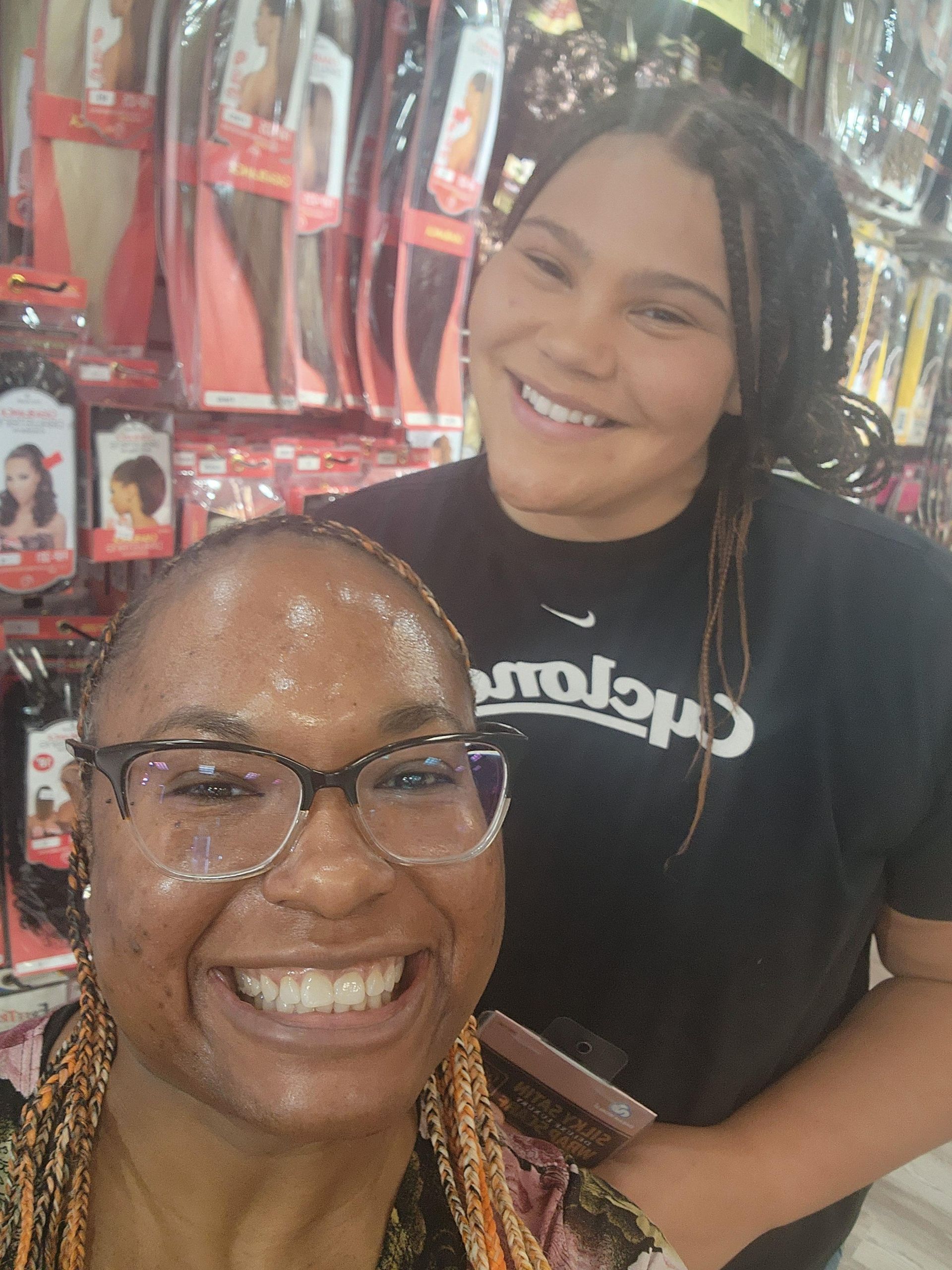Two smiling people in a store aisle, one holding a phone, with red packaged products on the shelves.