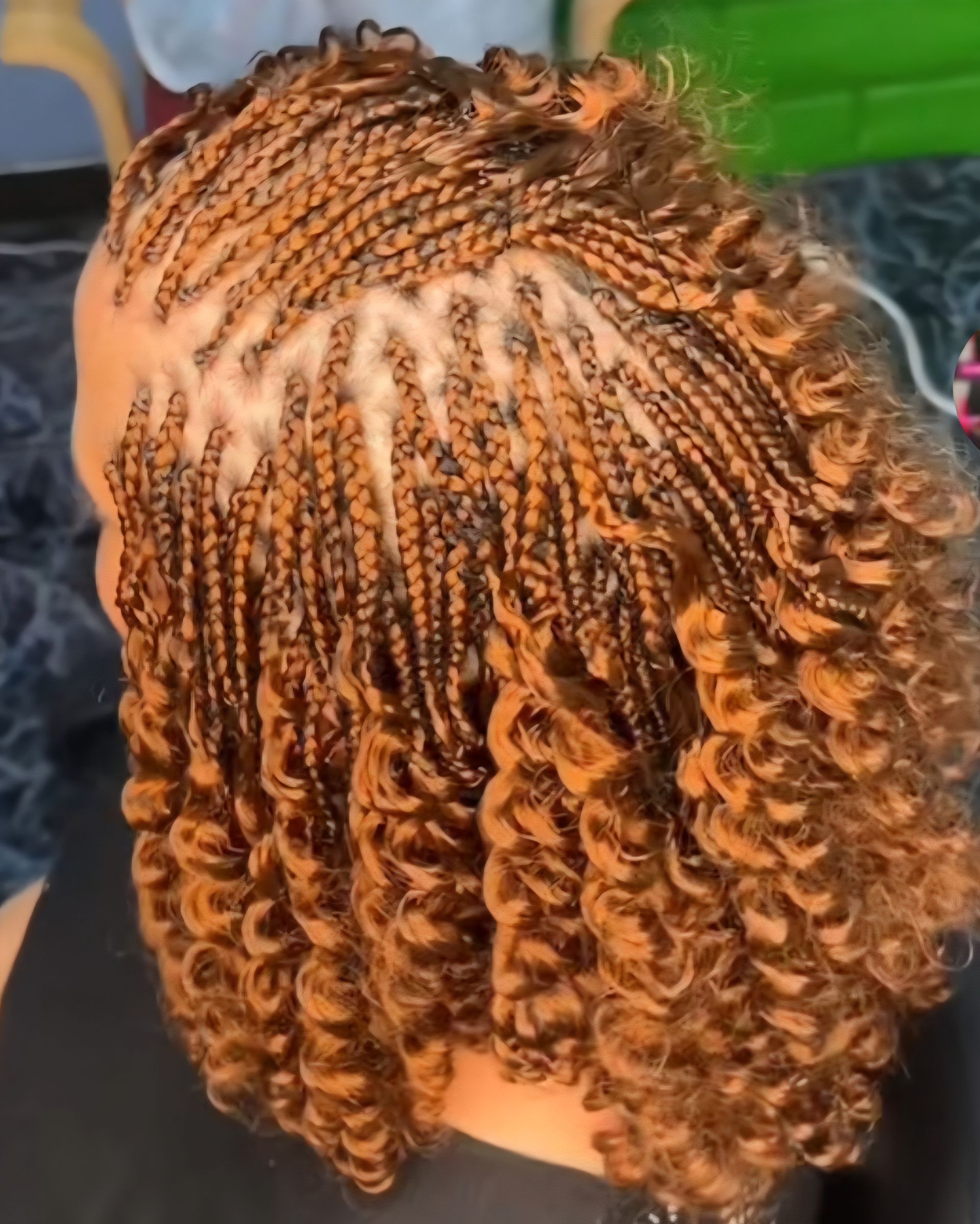 Close-up of orange and black braided hair styled in tight curls and cornrows