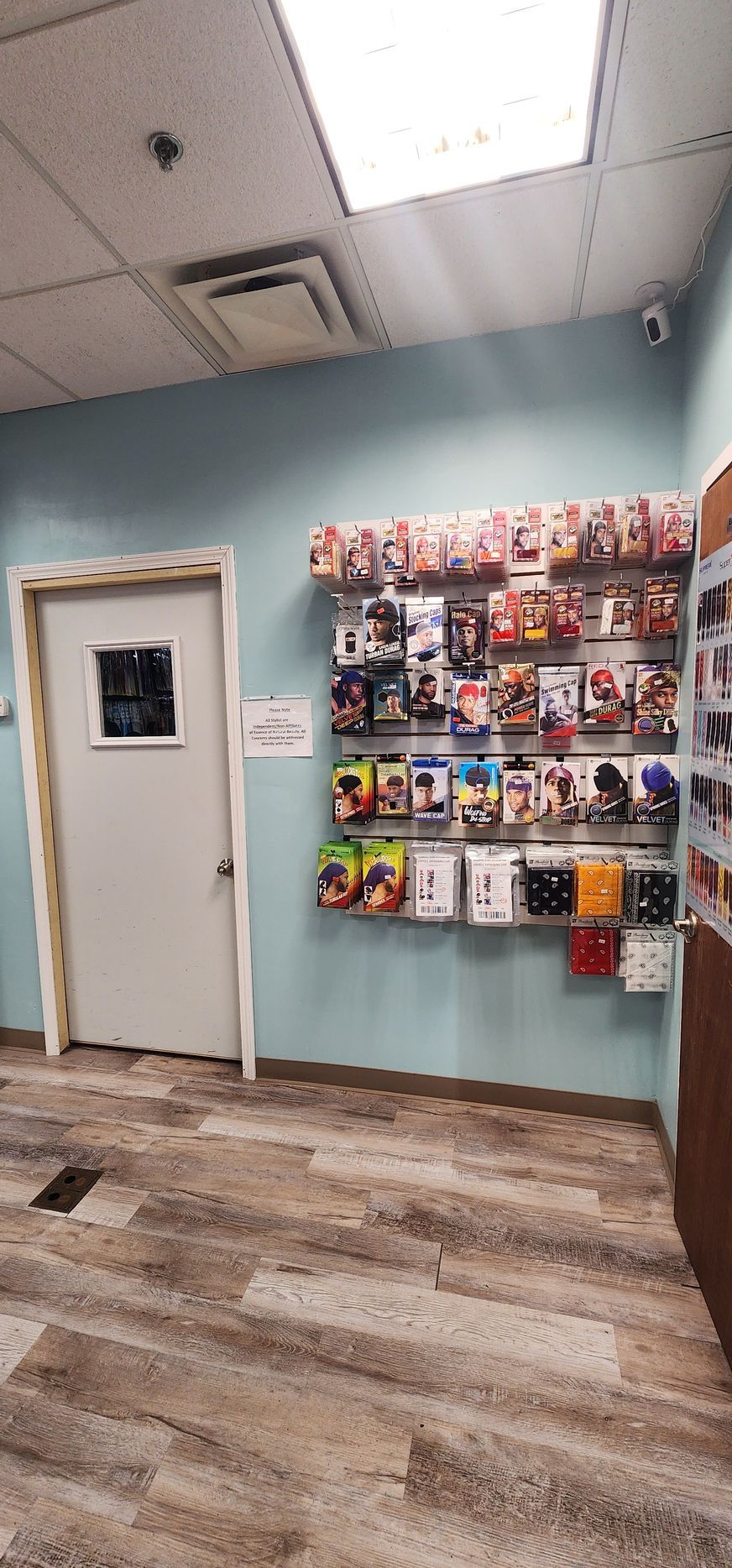Small office lobby with a white door, brochure rack, teal wall, and wood-look flooring.