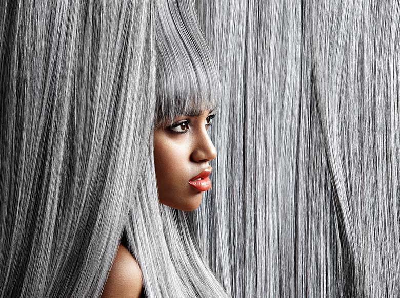 Woman with long, straight silver hair; profile view with serious expression.