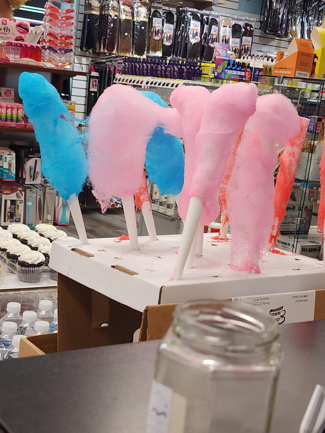 Cotton candy on sticks in blue and pink colors displayed at a shop counter