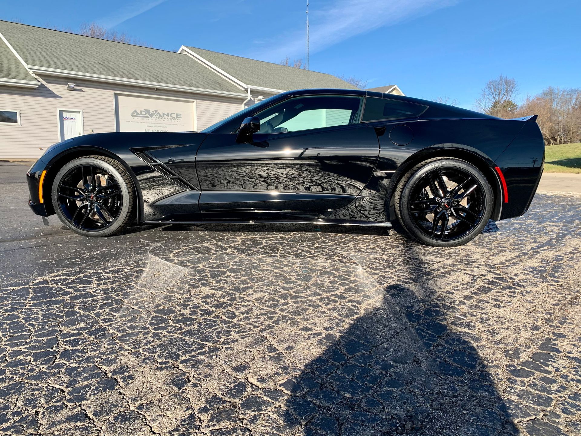 A black corvette is parked in a parking lot in front of a building.
