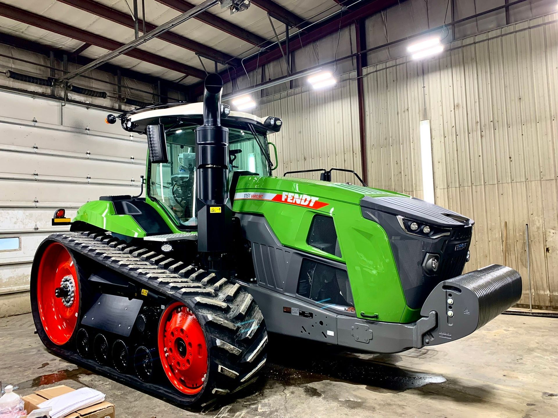 A green and black tractor is parked in a garage.