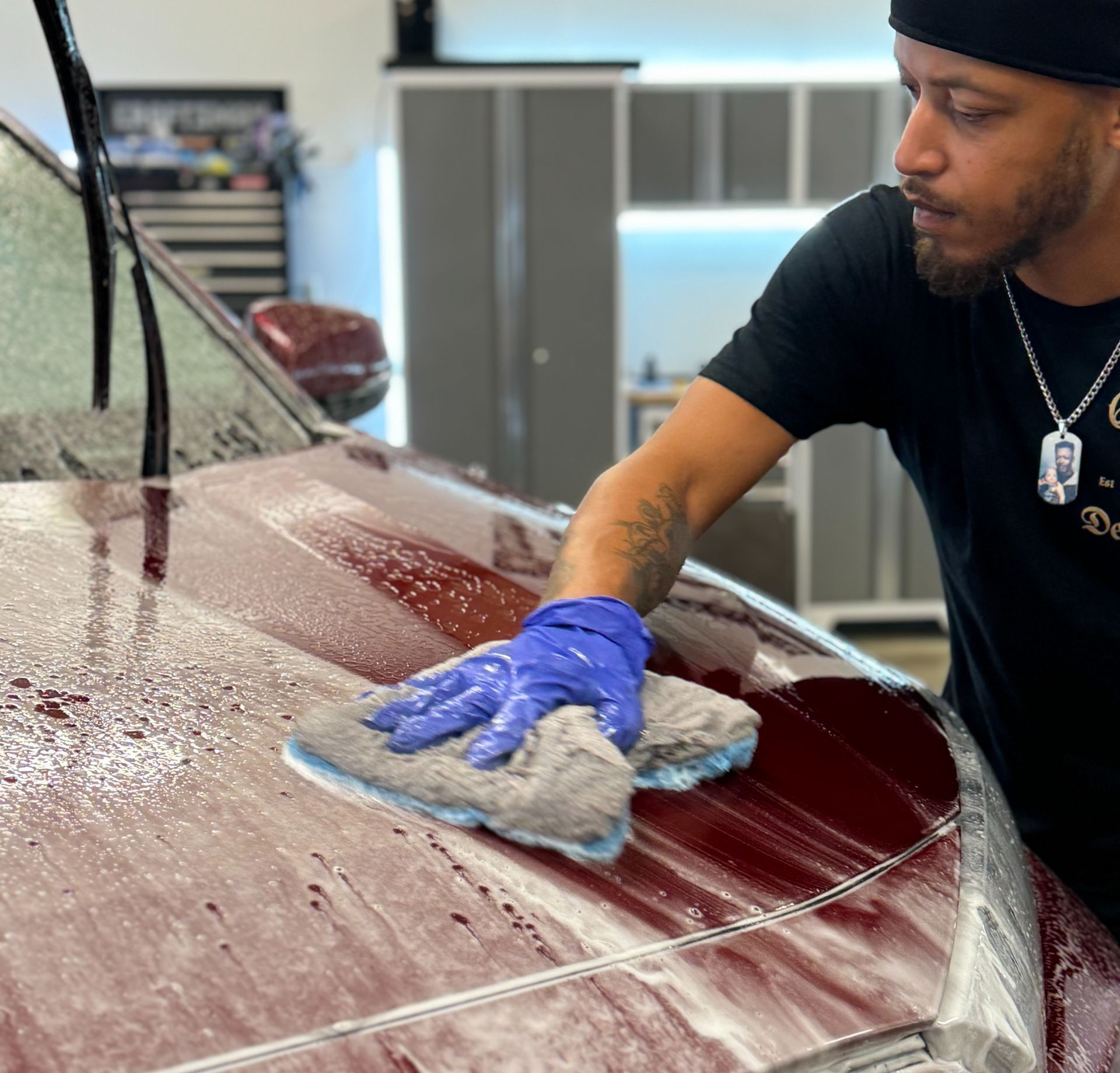 A man is washing a car with foam in a garage.