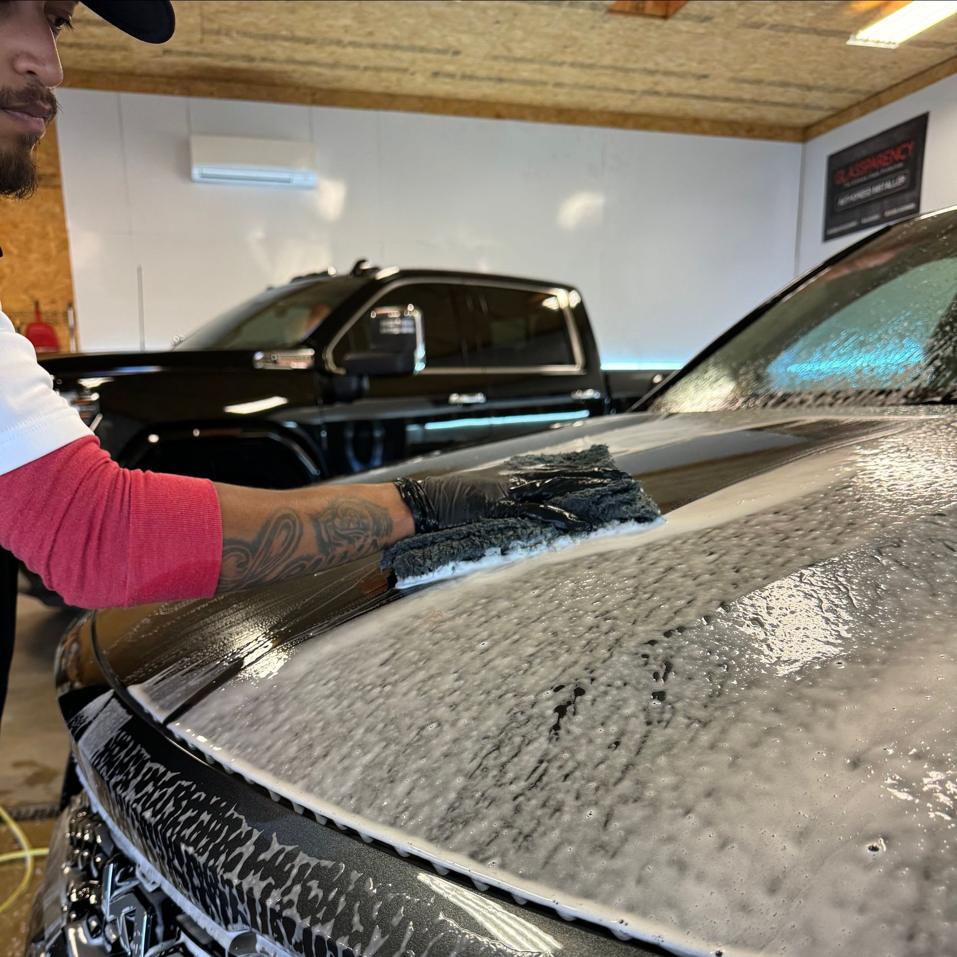A man is washing a black car in a garage