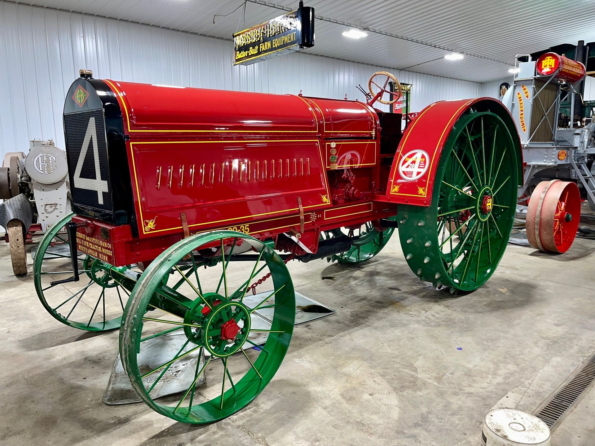 An old red tractor with green wheels is parked in a garage.