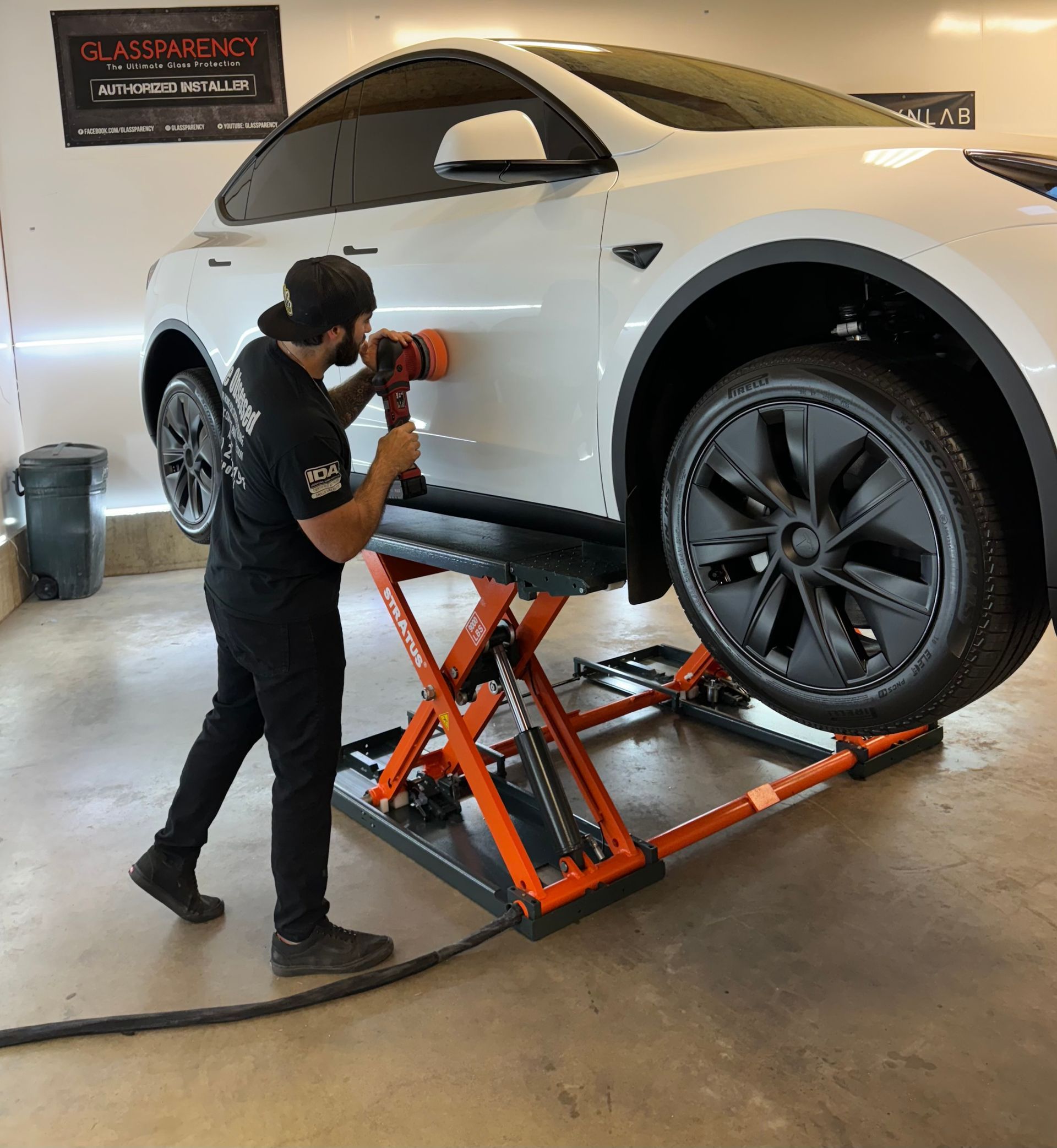 A man is polishing a white car in a garage.