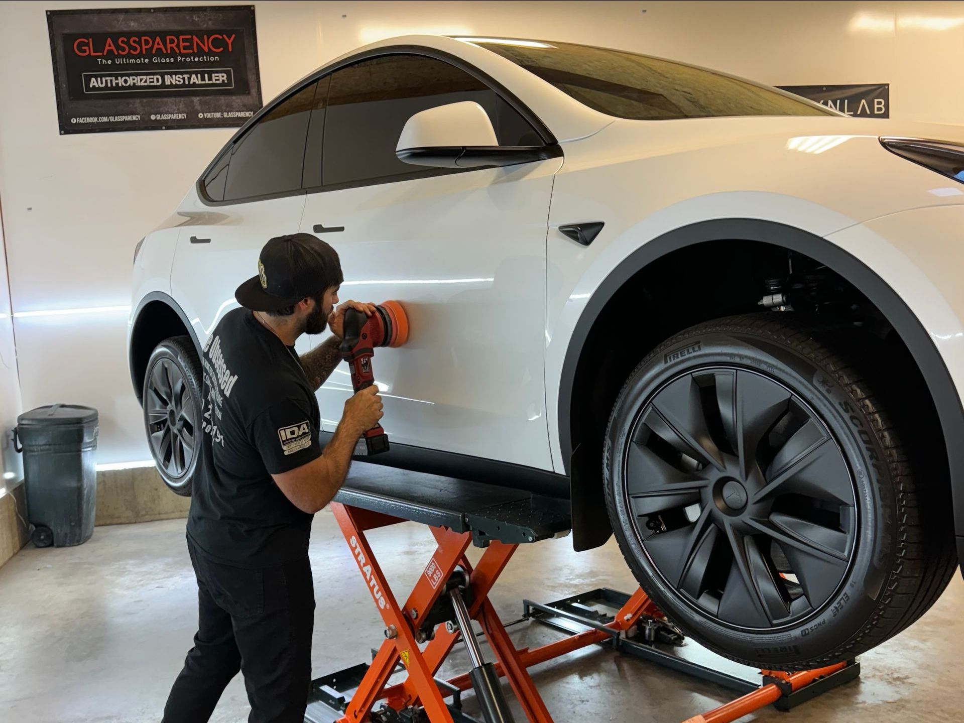 A man is polishing the side of a white tesla model y.