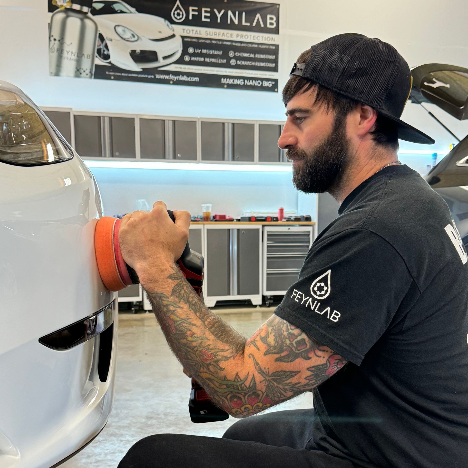A man is polishing the front of a car in a garage.