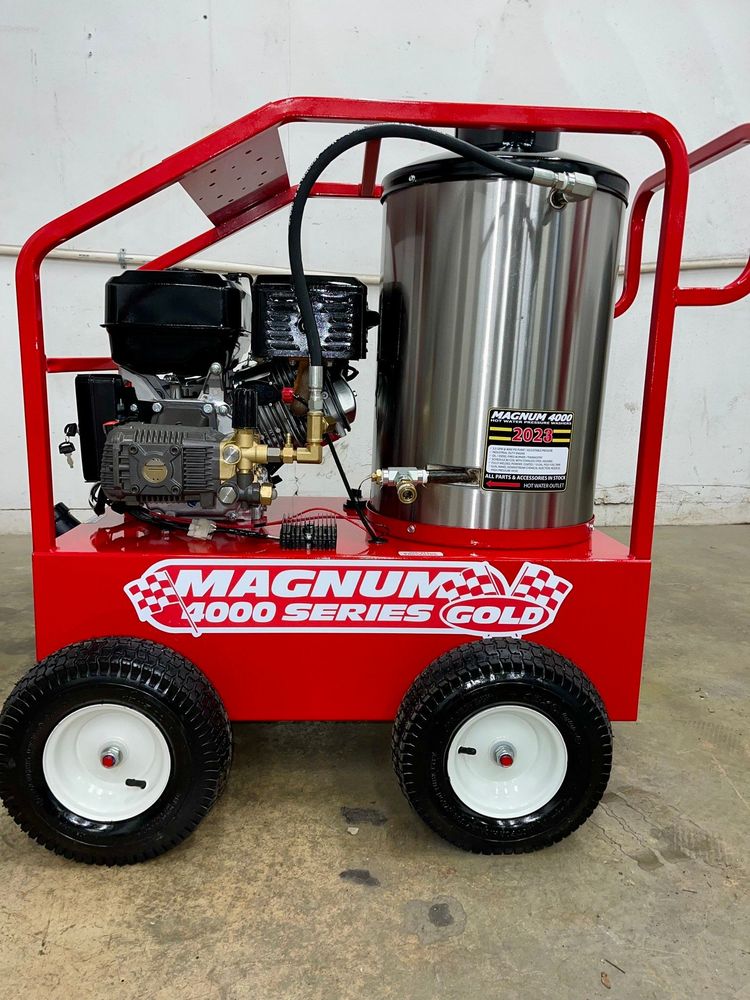 A red machine with a stainless steel tank is sitting on the ground.