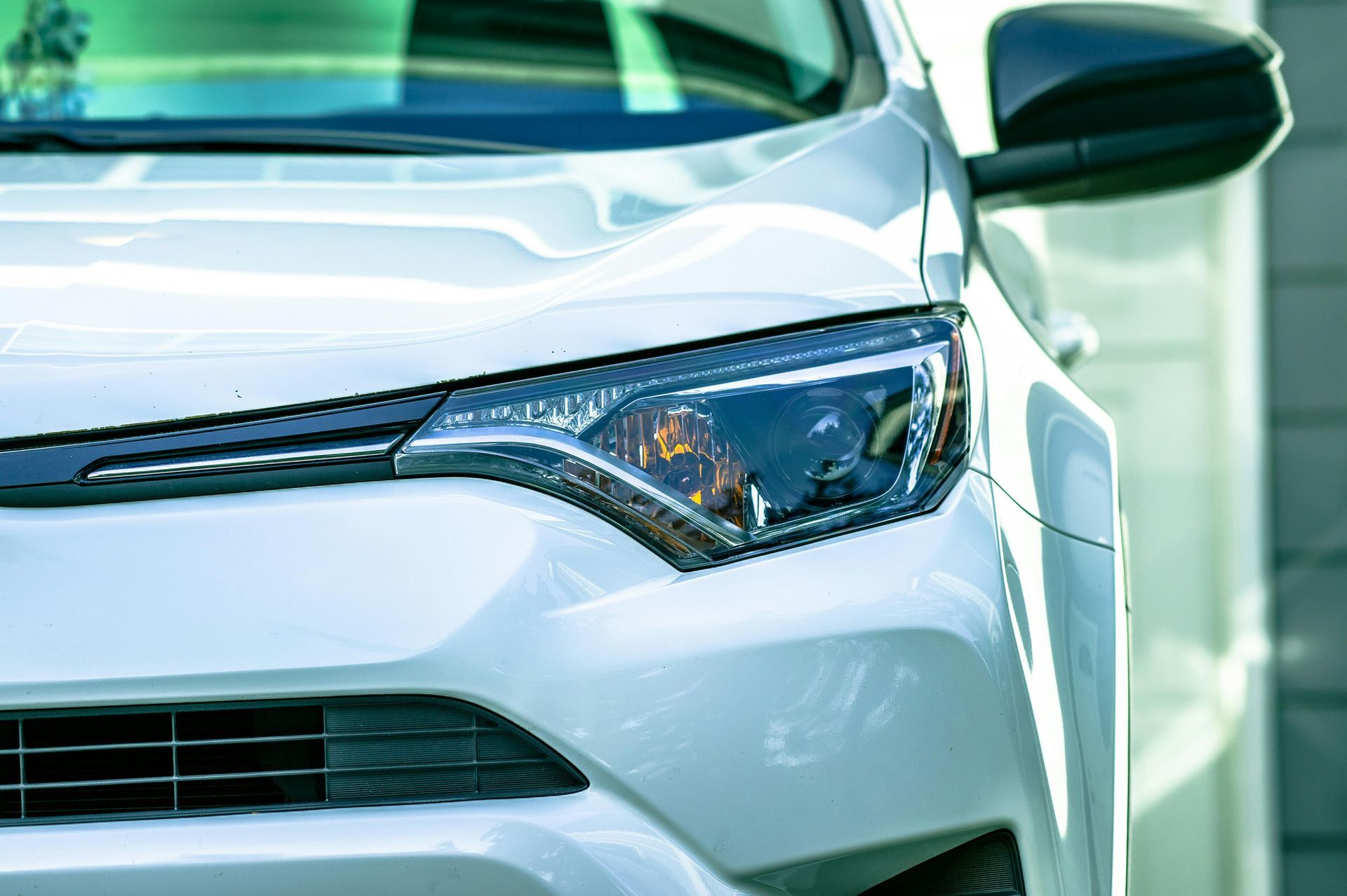 A close up of a white car parked in front of a building.