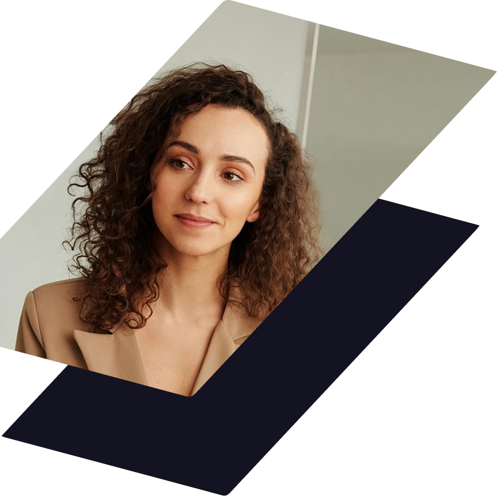 A person with curly hair wearing a tan blazer, looking slightly off-camera against a plain, light background.