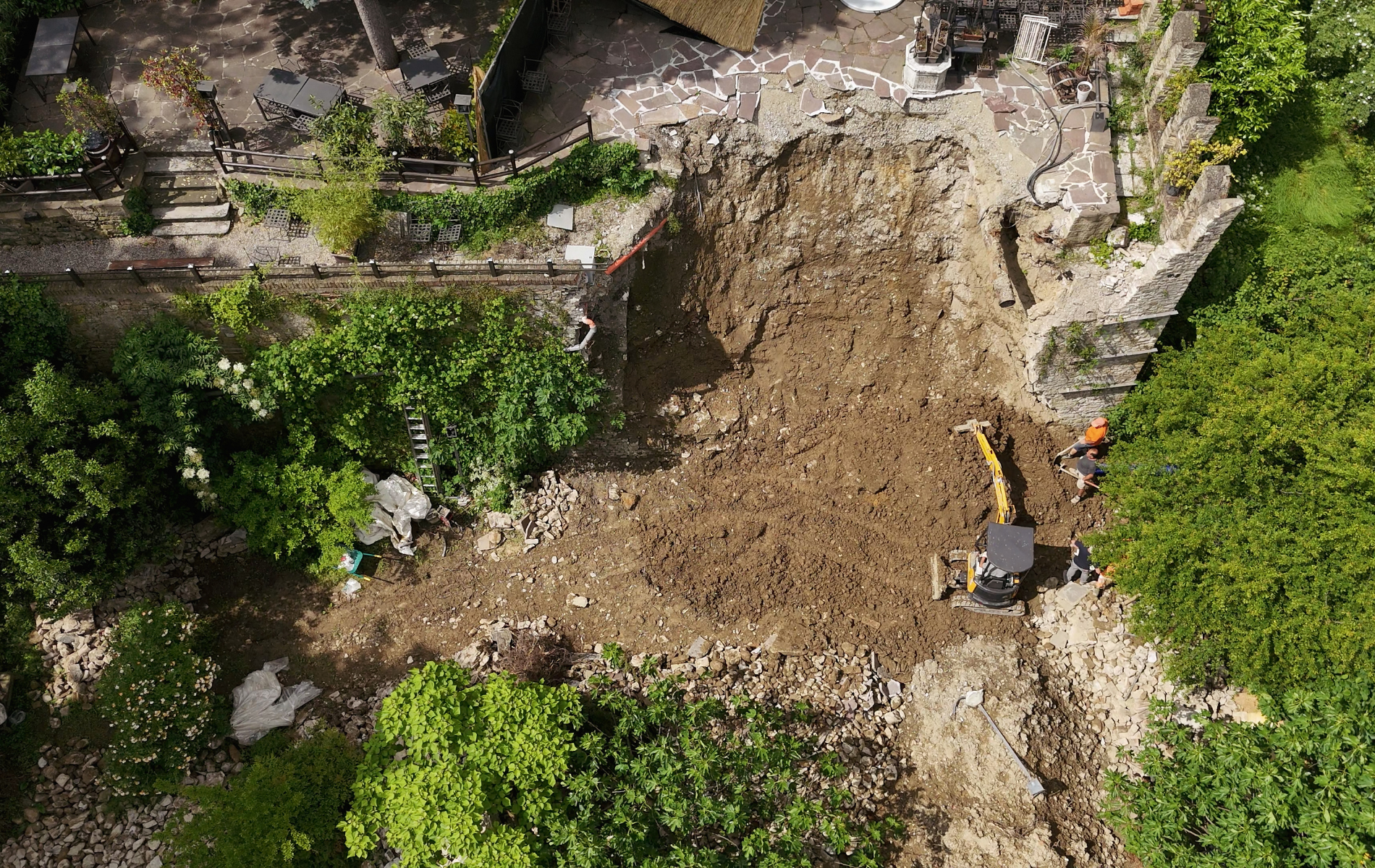 Yellow excavator loading dirt into a red dump truck, against a blue sky.