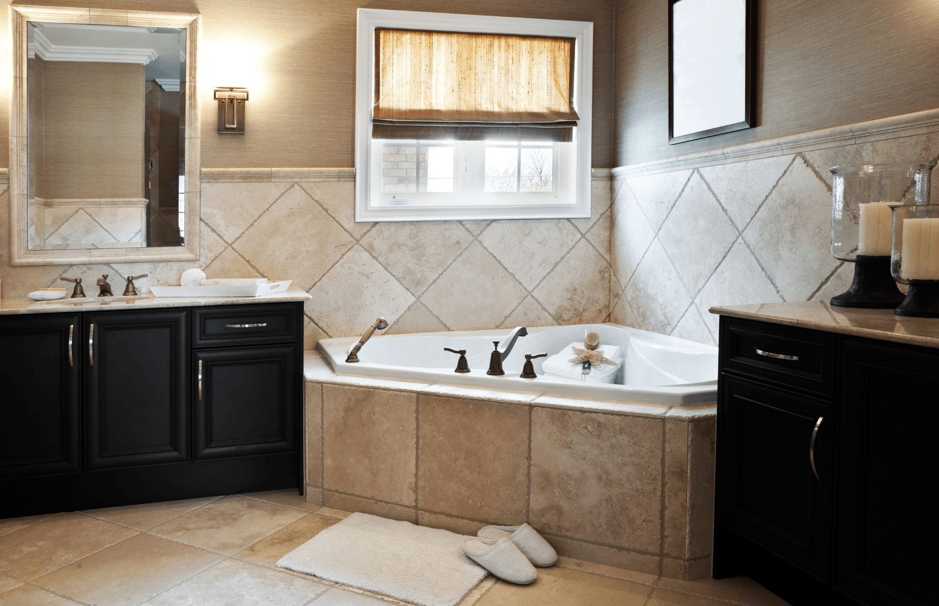 Elegant bathroom with a freestanding tub, dark vanities, tiled walls, and a lit window above the bath