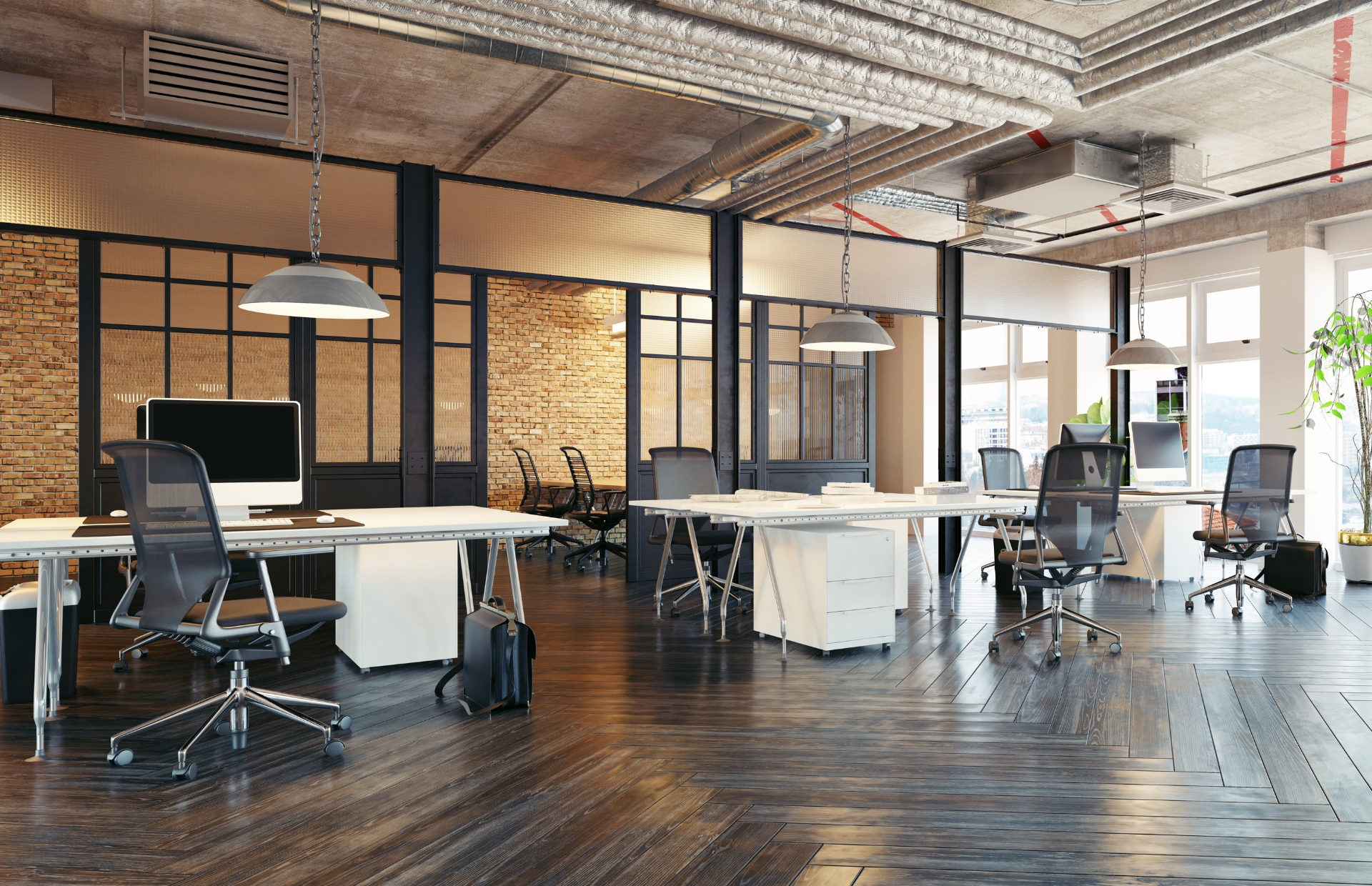 Modern open office with desks, chairs, computers, and large windows on a dark wood floor