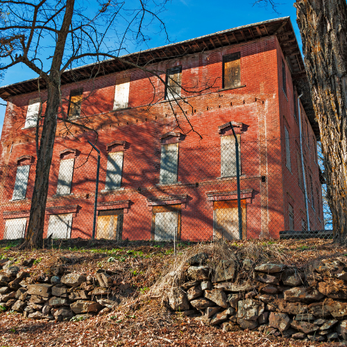 Red brick building on a wooded slope under a clear blue sky