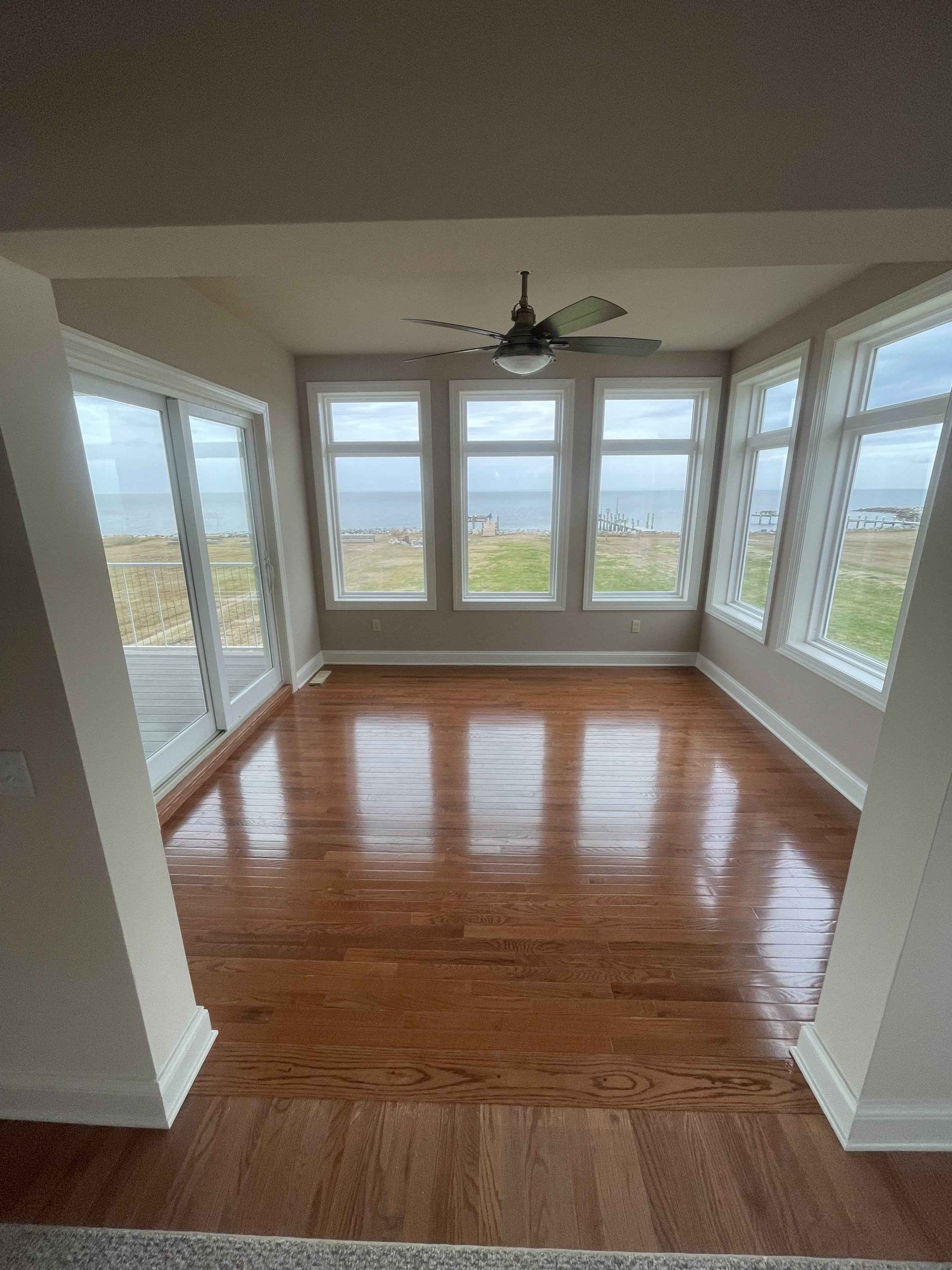 A living room with hardwood floors and a ceiling fan.