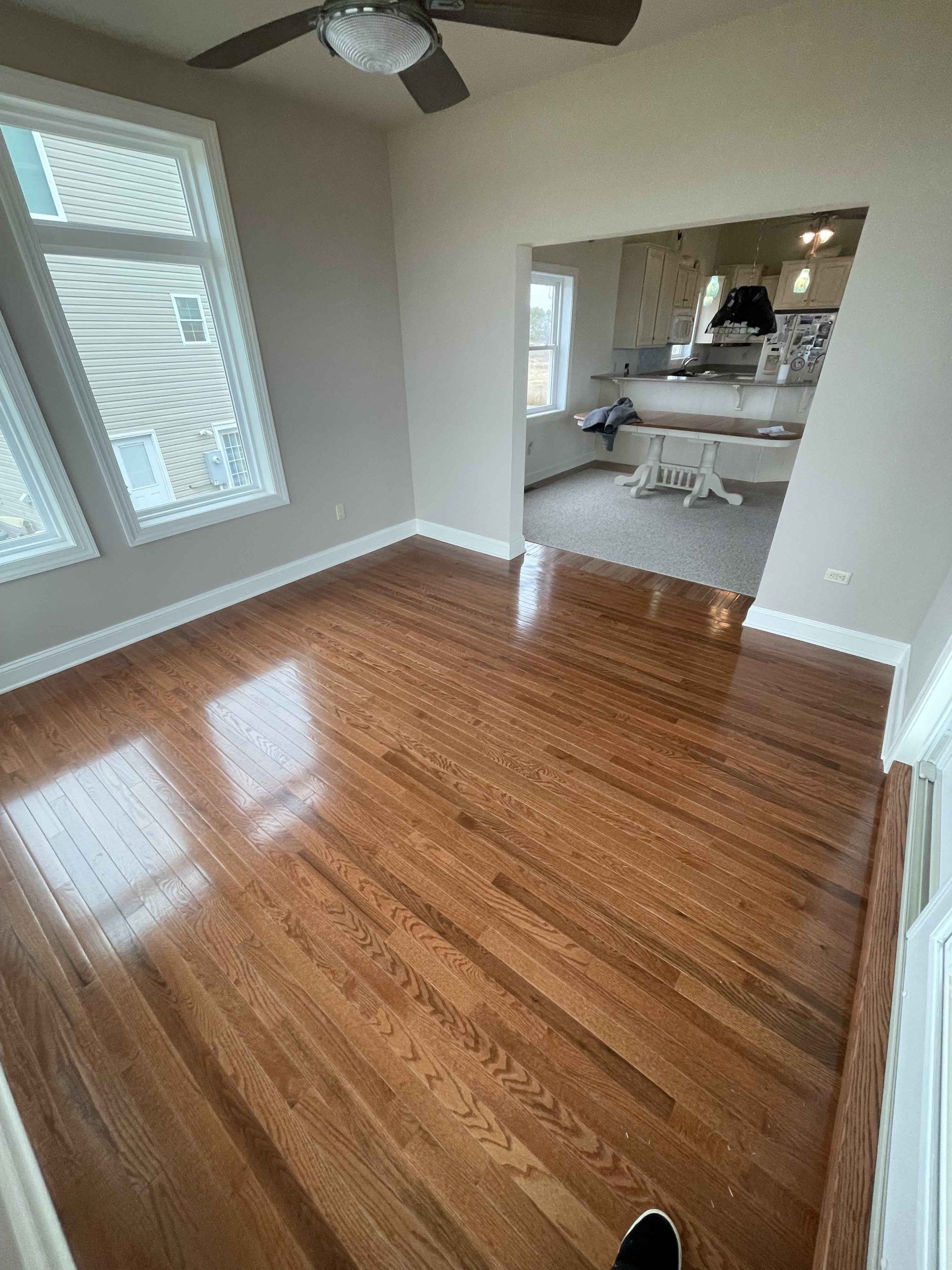 A living room with hardwood floors and a ceiling fan.