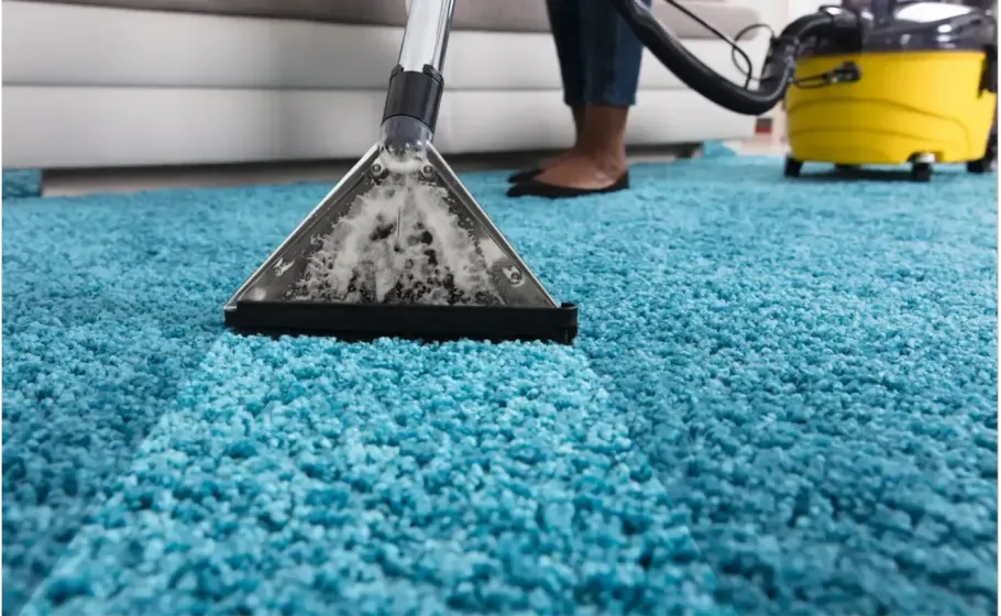 Carpet cleaner vacuuming a bright blue carpet in a room