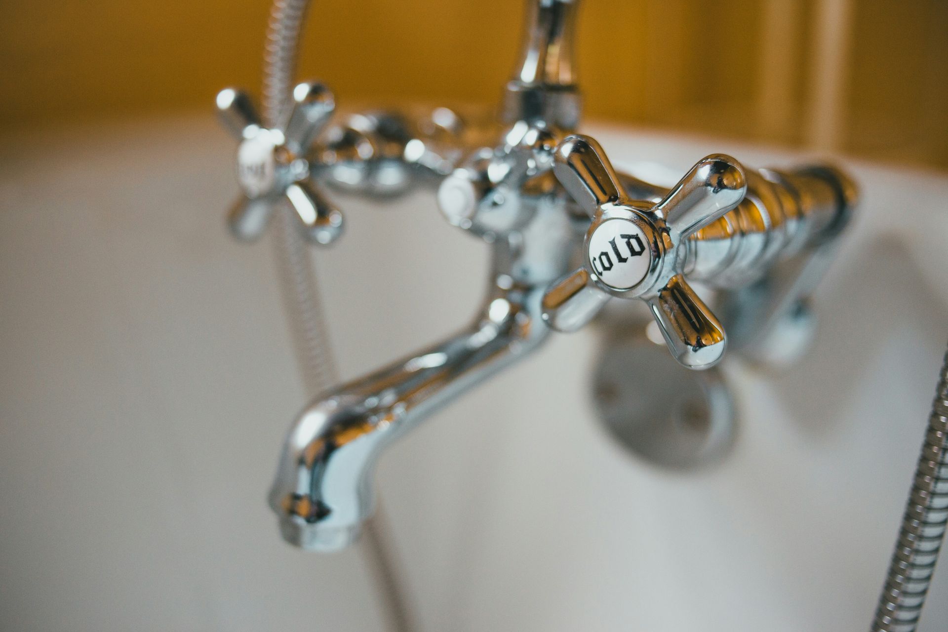 Hand turns faucet on, water splashes into a glass in a kitchen sink.