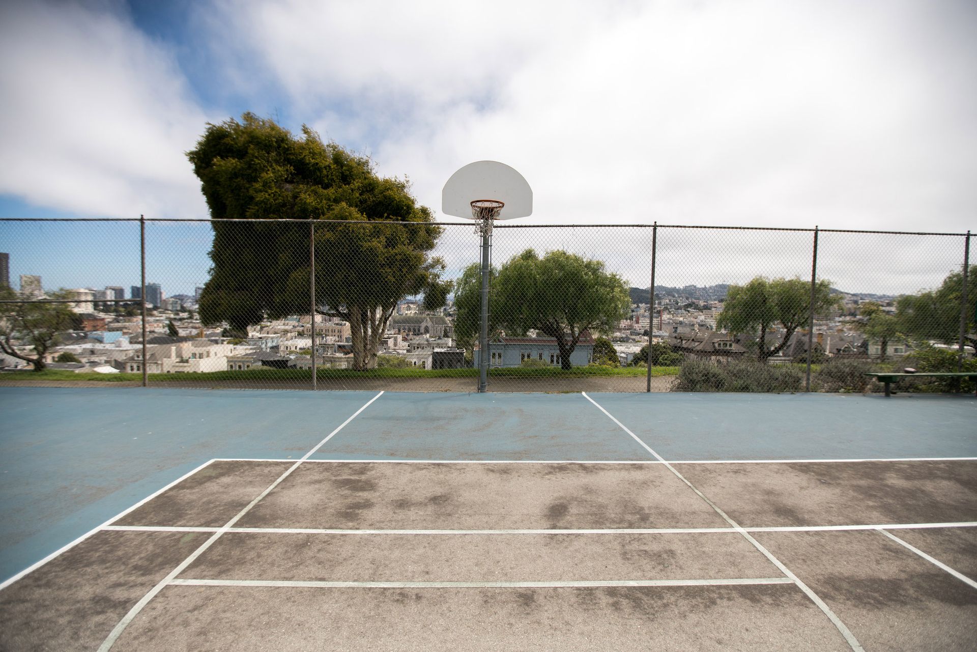 An empty basketball court with a city in the background.