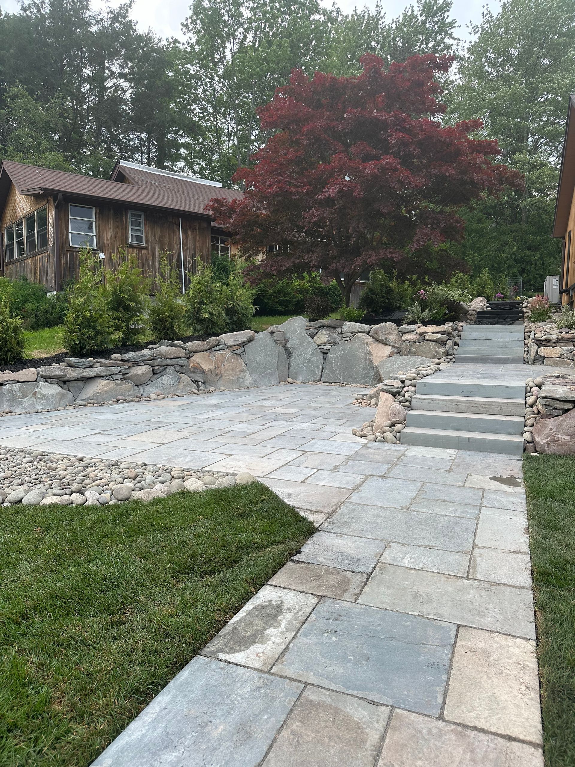 A stone walkway leading to a house with stairs.