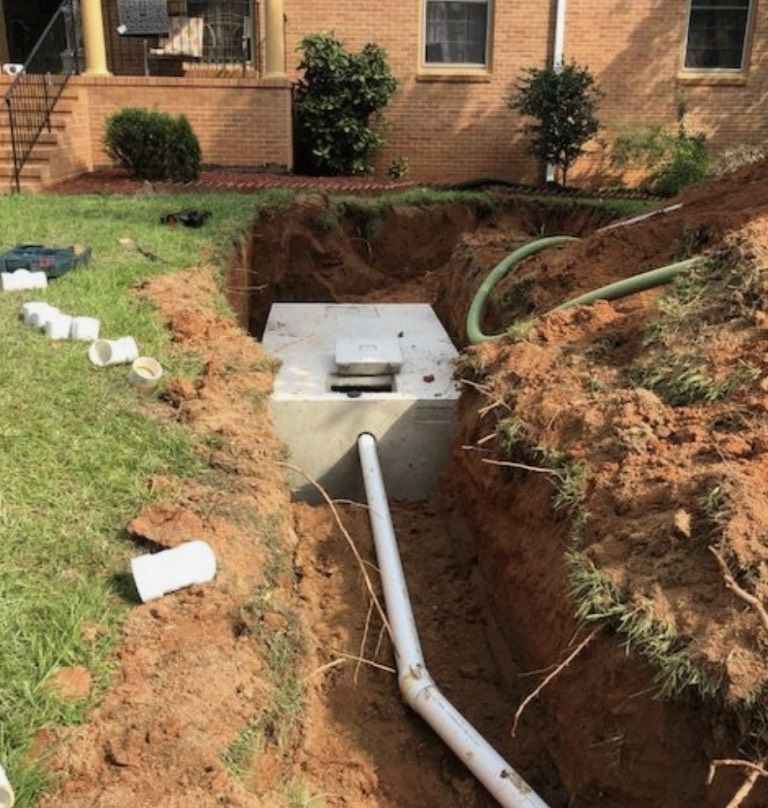 A septic tank is sitting in the dirt next to a pipe.