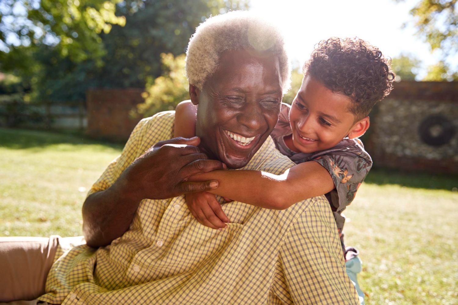 An elderly couple standing next to each other in front of a house holding hands.