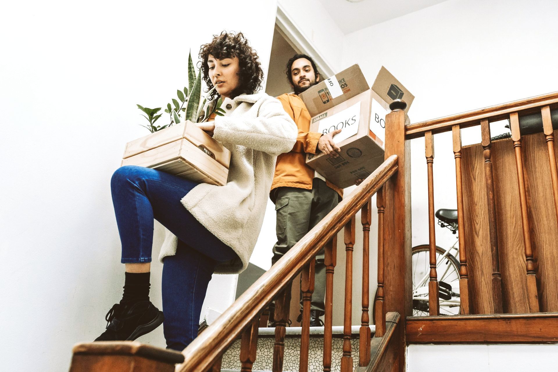 A man and a woman are carrying boxes up a set of stairs.