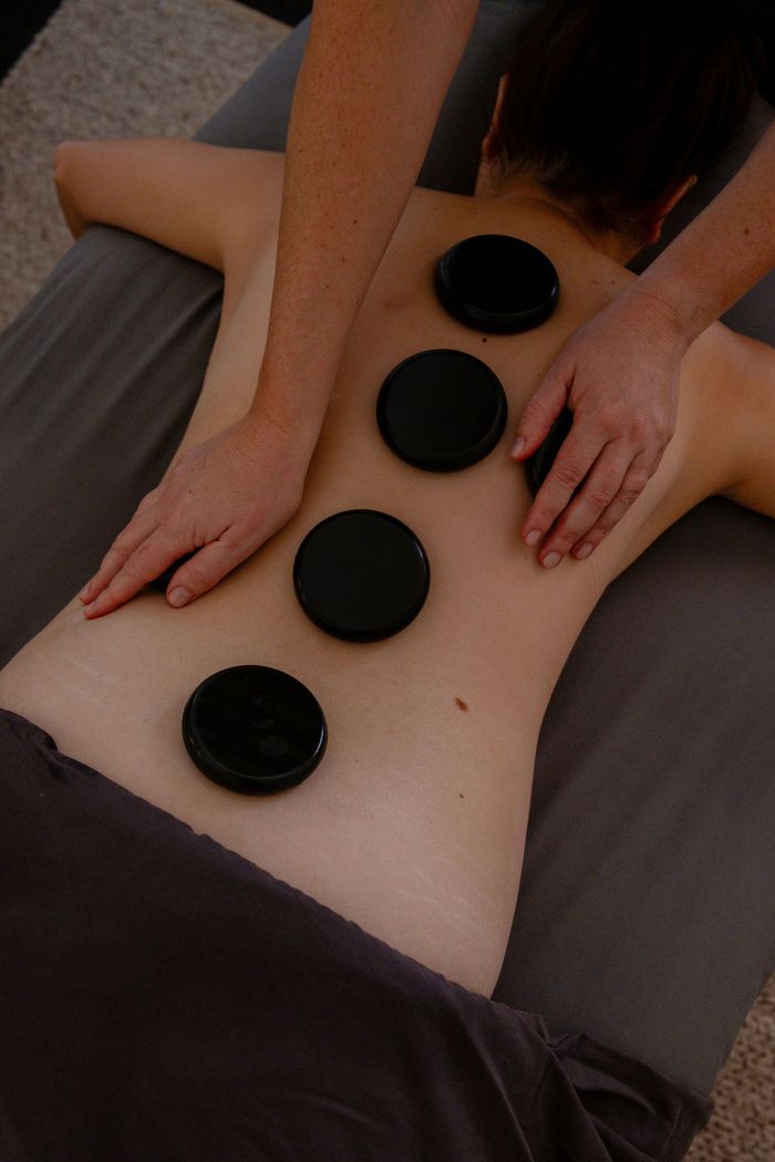 Back massage with four hot stones on the client’s back and two hands gently pressing