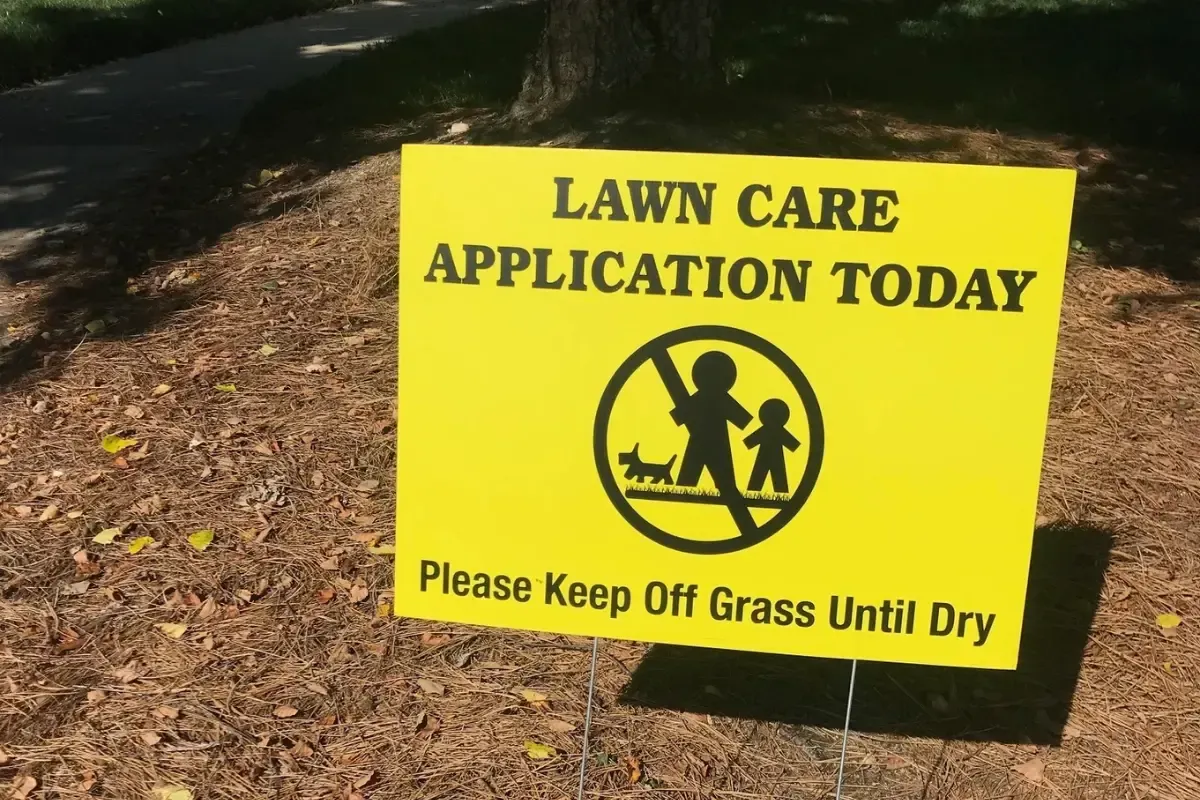 A sign on the ground that says lawn application today please keep off grass until dry