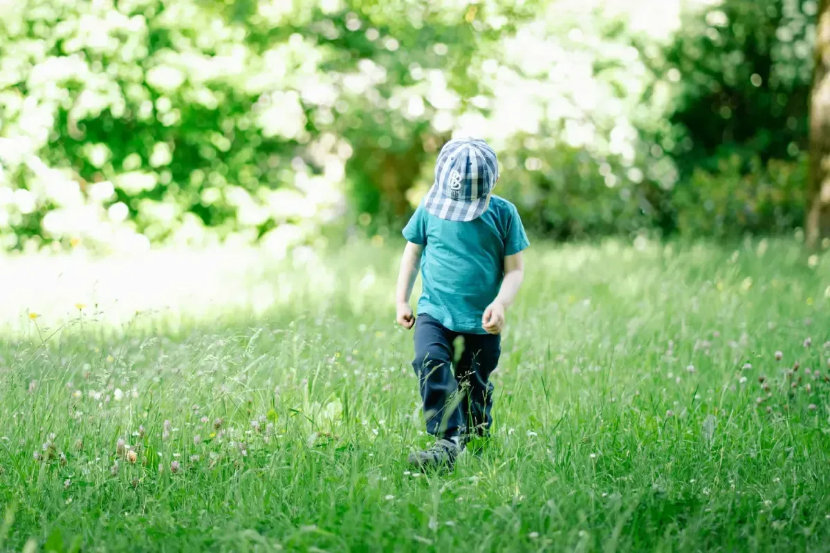 A boy walking on grass looking down