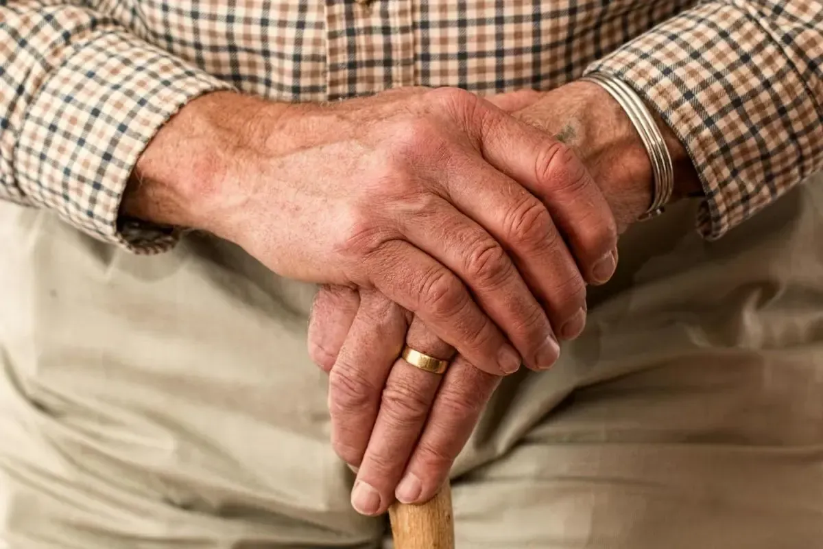 An elderly man's hands leaning on a cane