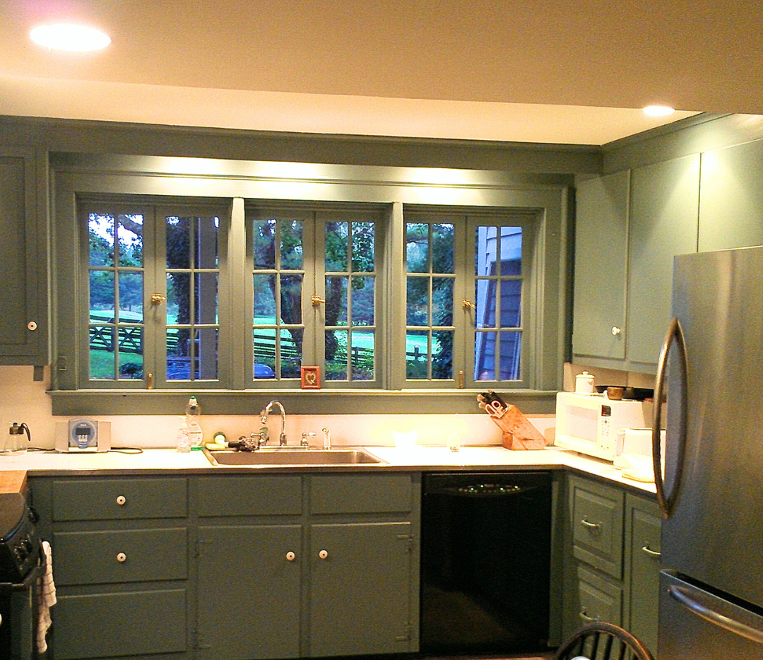 A kitchen with green cabinets and a sign that says cabinet painting