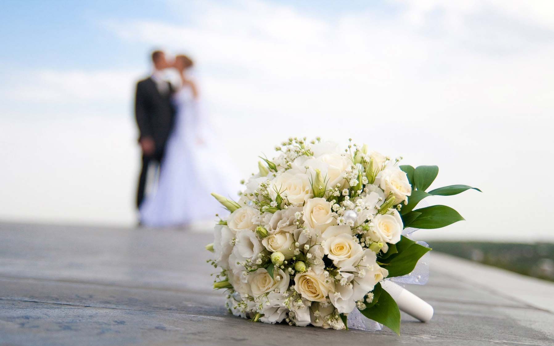 la sposa e lo sposo si baciano sullo sfondo di un bouquet di fiori