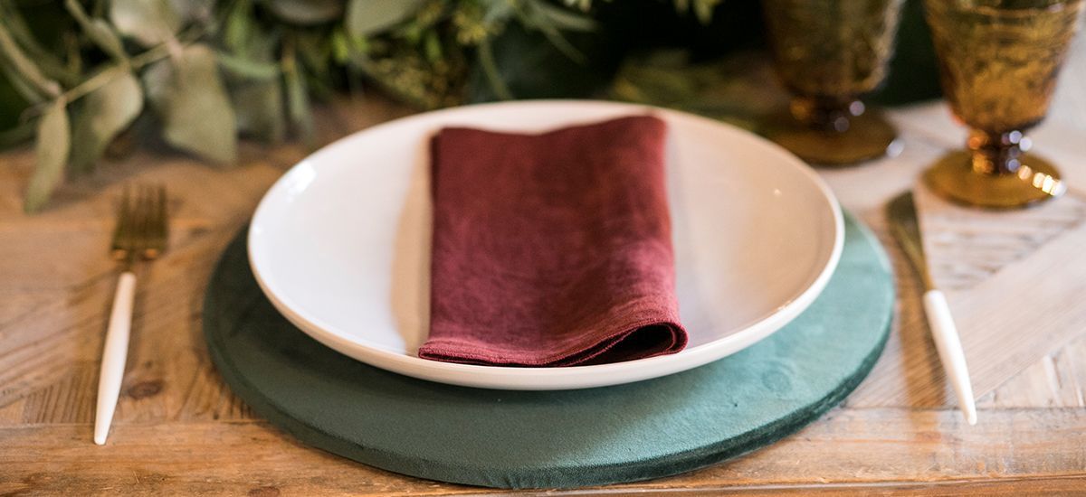 a white plate with a burgundy napkin and white cutlery