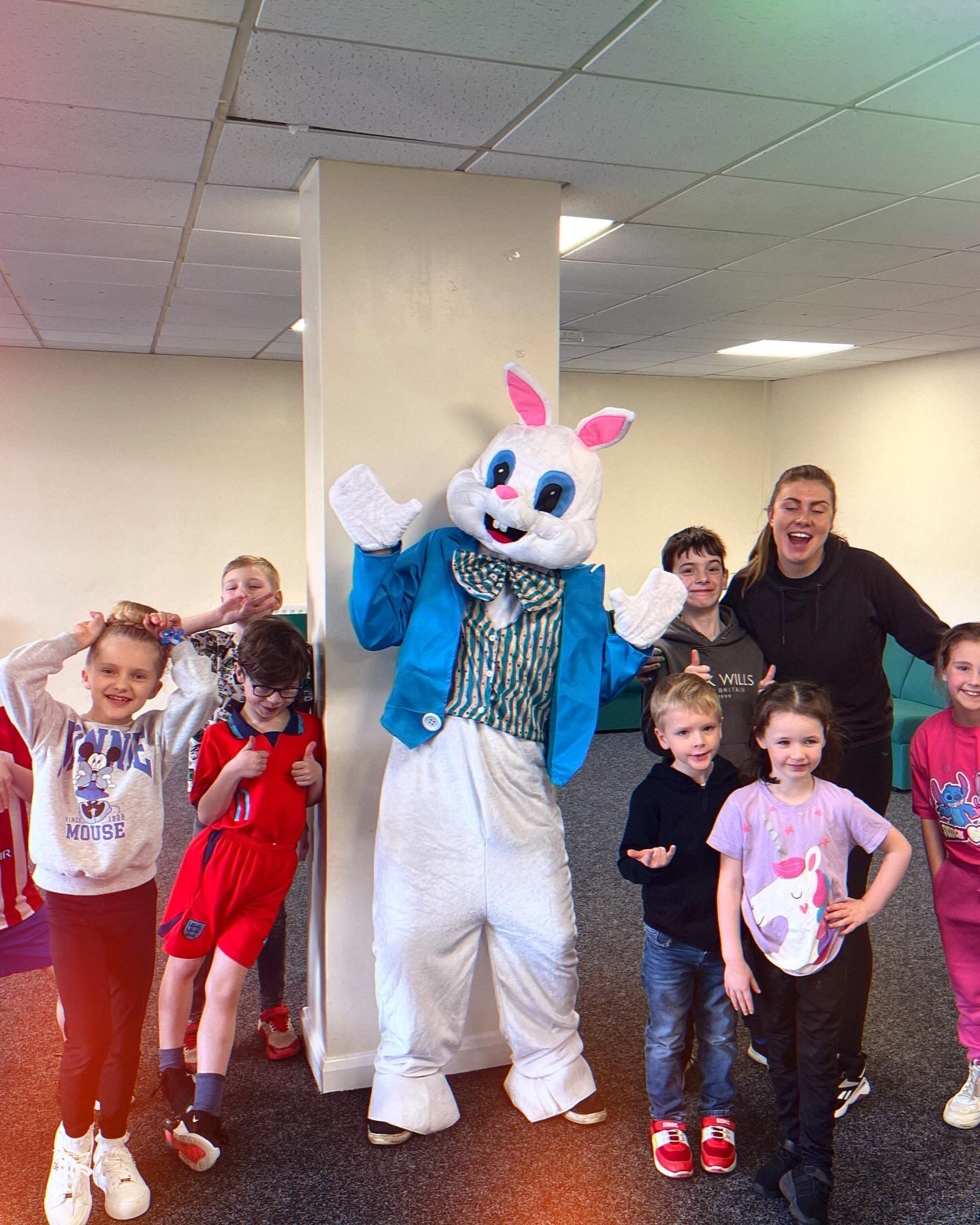 A group of children are posing for a picture with a bunny mascot.