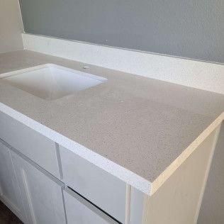 White bathroom vanity with a square sink and beige countertop against a gray wall