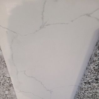 White marble-look planter or vase with faint gray veining on a speckled countertop