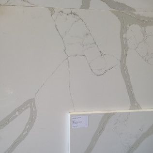 White marble tile with gray veining and a small corner label sample at the bottom right