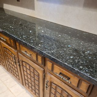 Black granite countertop above wooden cabinet doors with lattice panels and silver handles